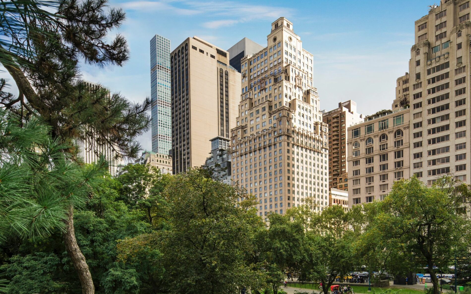 the Ritz-Carlton New York, Central Park on the edge of Central Park surrounded by trees with sky scrapers behind. luxury travel lifestyle pr